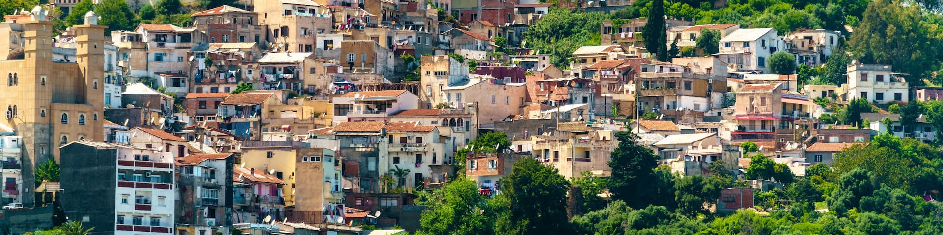 A densely packed hillside town with historic buildings and a prominent church with a dome.