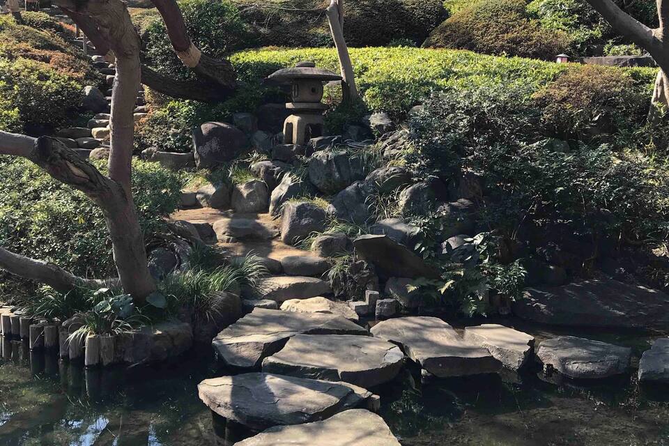 Un pont de pedra sobre un estany envoltat d'arbres i un pagoda.