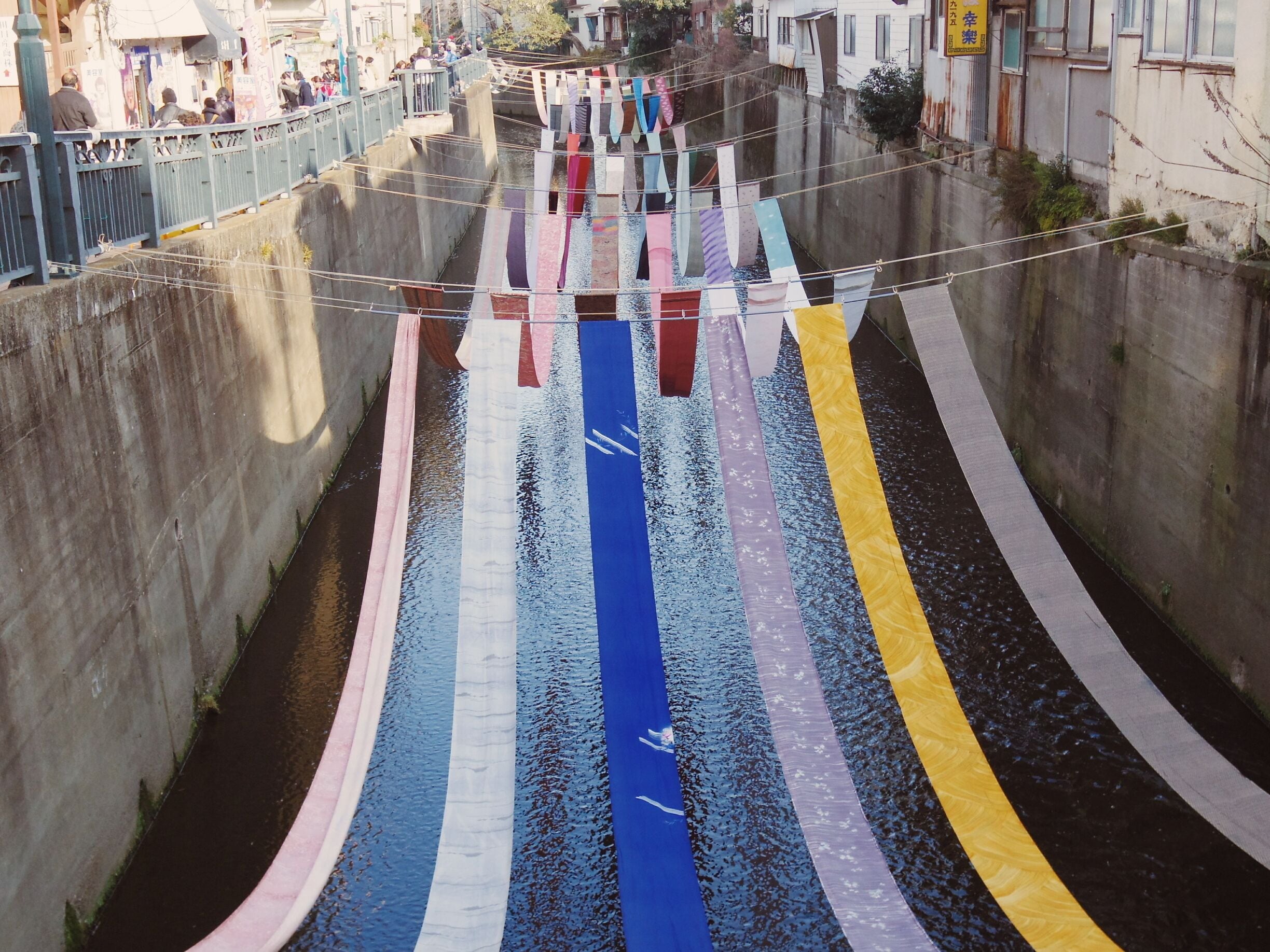 Some No Komichi (染の小道) is an event that showcases the art of traditionally dyed fabric, which was one of Shinjuku's largest industries in the early 1900s. There are still several small factories in the area that keep this tradition alive.

During the event, Myoshoji River turns into a gallery with colorfully dyed fabric flowing in the wind. The shops in the surrounding area of Ochiai and Nakai also participate by hanging beautiful curtains called "noren," made from dyed fabric, in front of their doors and windows.

*Many people come to this event wearing kimonos. There's also a kimono rental shop here, if you want to wear one for a day as well.

*Some No Komichi is held in Nakai (Shinjuku-ward, Tokyo) every year in late February.

*More photos here: http://goo.gl/6y98JP