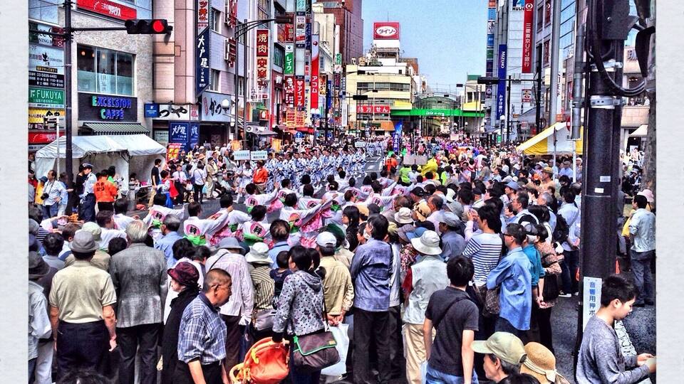A crowded street with people, buildings, and signs.