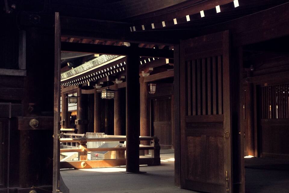 A traditional wooden building with a large open door, columns, and a tiled roof.