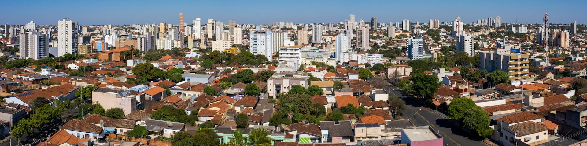 A cityscape with dense residential buildings, a clear blue sky, and a mix of high-rise and low-rise structures.