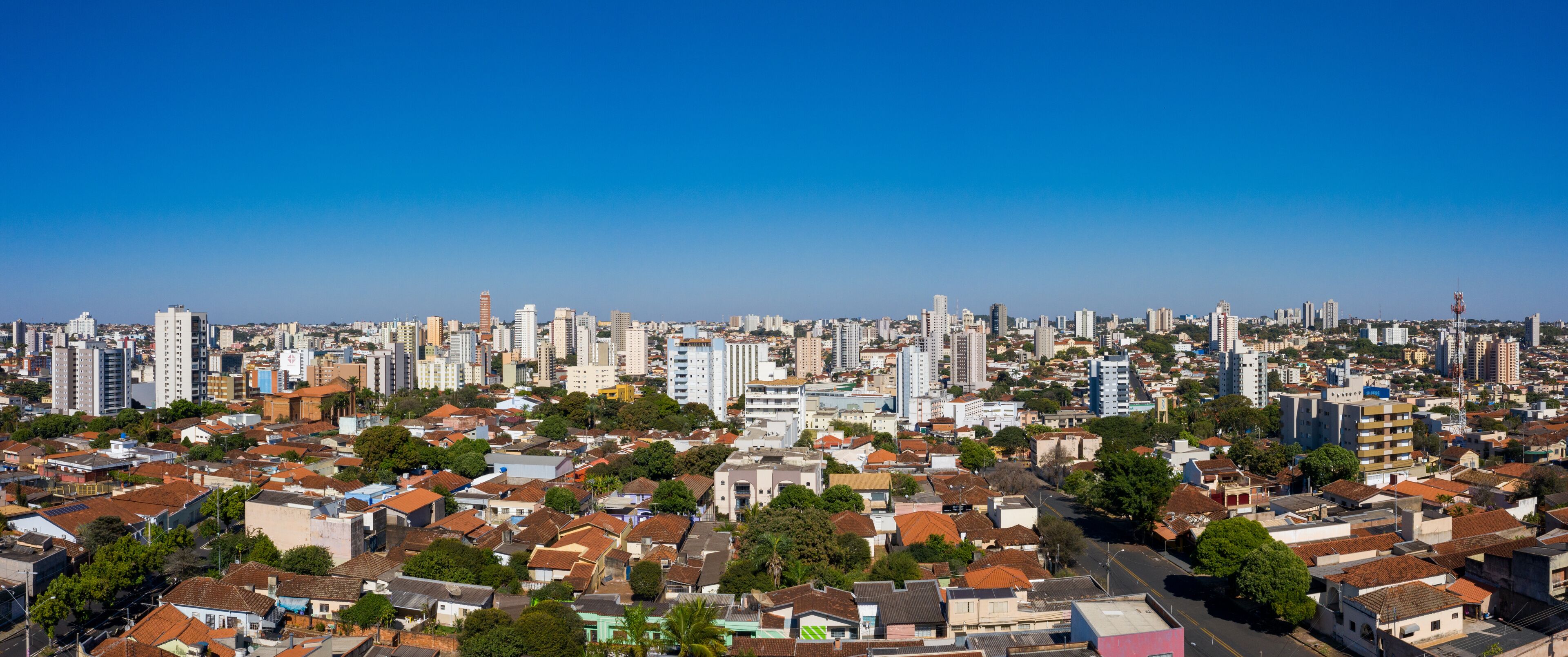 A cityscape with dense residential buildings, a clear blue sky, and a mix of high-rise and low-rise structures.