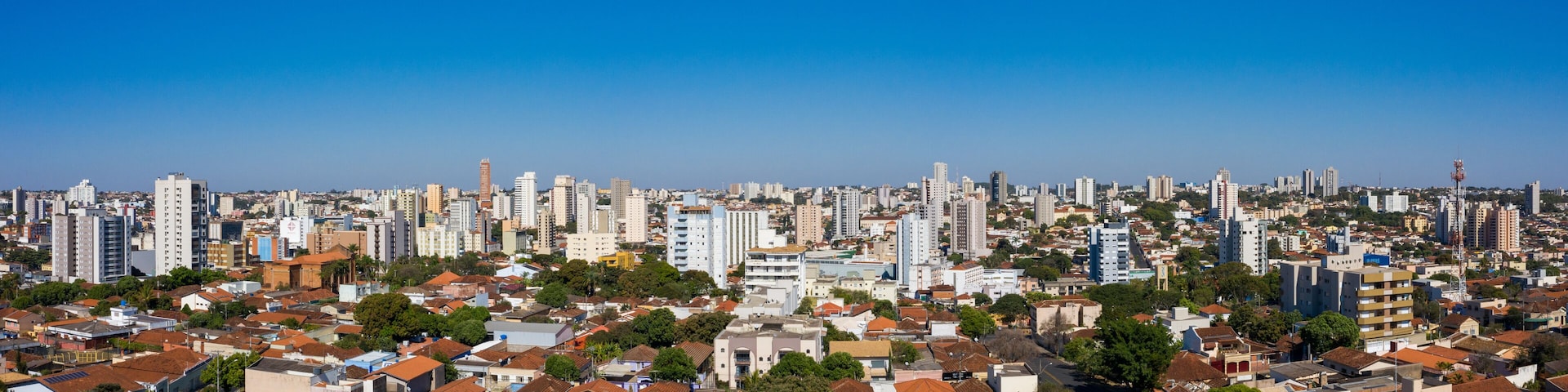 A cityscape with dense residential buildings, a clear blue sky, and a mix of high-rise and low-rise structures.