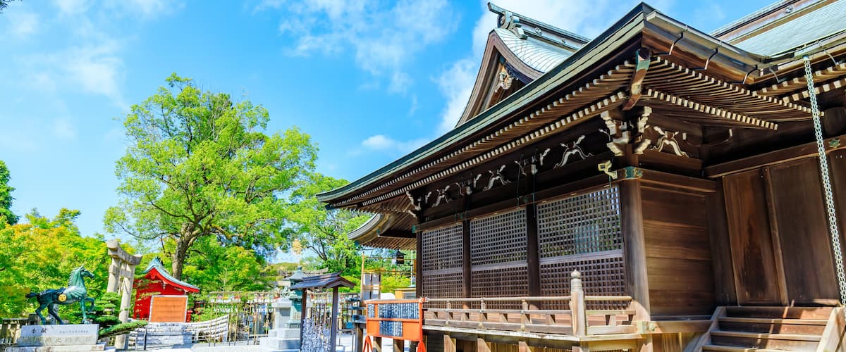 A traditional Japanese building with a wooden structure, a red-roofed pavilion, and a stone statue of a horse.
