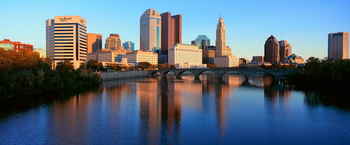 A city skyline with a river and a bridge.