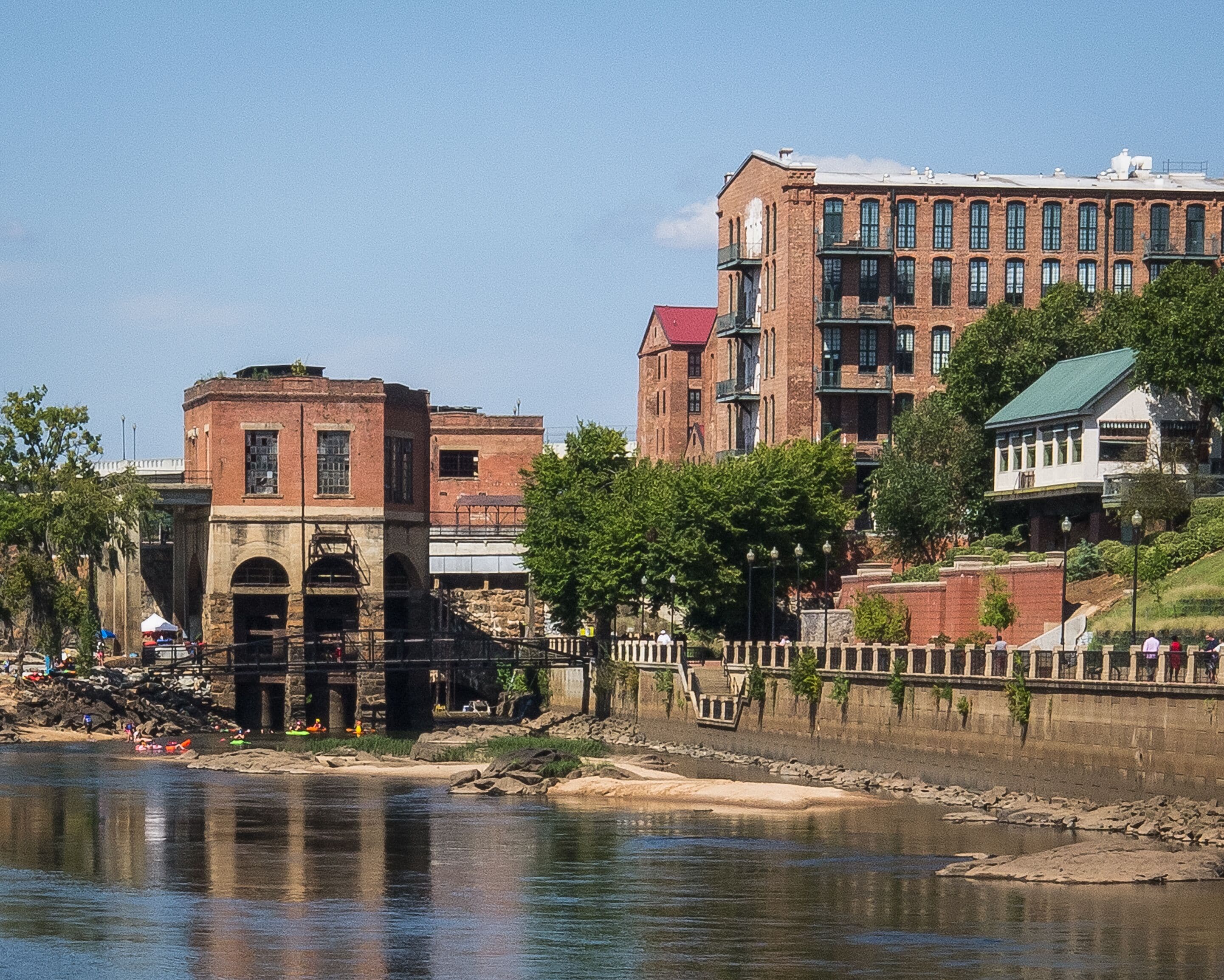 Chattahoochee River shoreline as it passes through Columbus, Georgia on a sunny weekend day with rafters and kayakers preparing to enjoy a day of drifting on the river.
