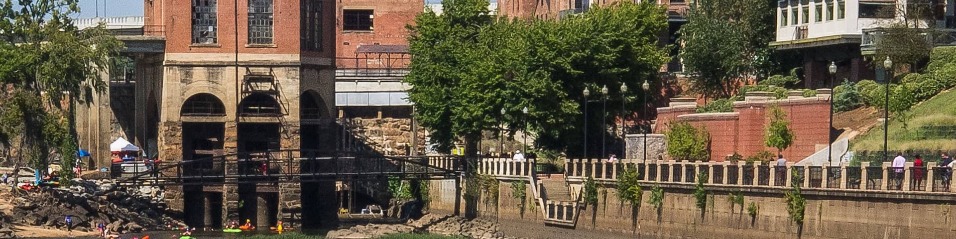 Chattahoochee River shoreline as it passes through Columbus, Georgia on a sunny weekend day with rafters and kayakers preparing to enjoy a day of drifting on the river.