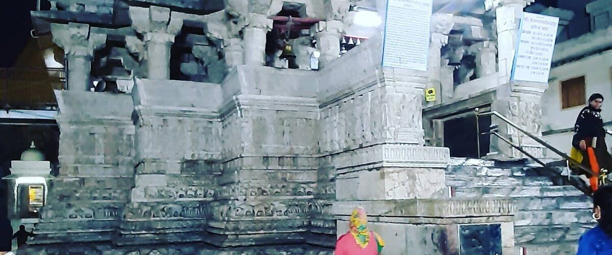 Jagdish Temple is one of the famous temples of Udaipur. Located in the City Palace complex of Udaipur, this temple is made in the Indo-Aryan style of architecture. In 1651, Jagdish temple was built by Maharana Jagat Singh, who ruled Udaipur during 1628-53. The temple is dedicated to Lord Vishnu (Laxmi Narayan), the preserver of the Universe. It is celebrated for being the largest temple in the city of Udaipur. The gateway of this temple can be sited at a distance of 150 meters from the Bara Pol of the City Palace.
This three-storied temple is a wonder of architecture that comprises beautifully carved pillars, decorated ceilings, painted walls and lush halls. In those times, 1.5 million rupees were spent to raise this structure. The spire of the main temple is around 79 feet high that undoubtedly dominates the skyline of Udaipur. This shikhar (spire) is festooned with sculptures of dancers, elephants, horsemen and musicians making it truly a sight to behold.
As and when you approach the temple, you will be welcomed by two huge stone elephants at the entrance. On the very front of the temple, you would find a stone slab that is imprinted with the inscriptions with reference to Maharaja Jagat Singh. To reach the main shrine, you have to take a marble flight of 32 steps. Here, you will find a brass image of Garuda, a figure of half-man and half-eagle. This huge idol stands as if; it is guarding the doorway of Lord Vishnu.