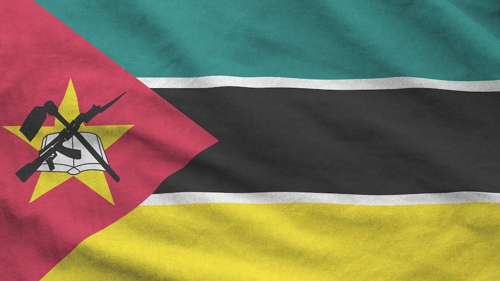 Mozambique flag depicted on folded wavy fabric of old cloth close up