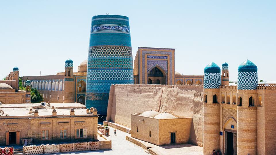 A historic cityscape with traditional architecture, including a tall blue tower and domed buildings.