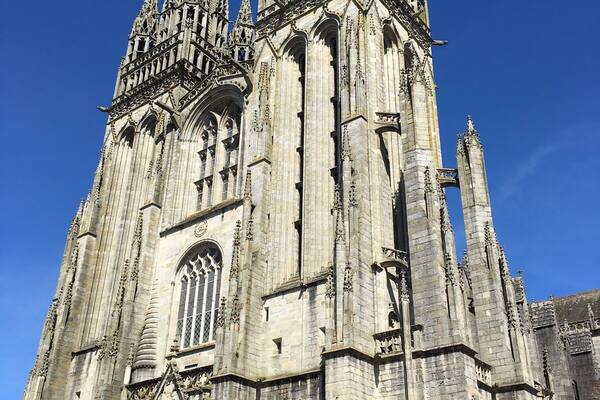 Une vaste cathédrale gothique, ornée de sculptures complexes en pierre et surmontée de flèches élancées.
