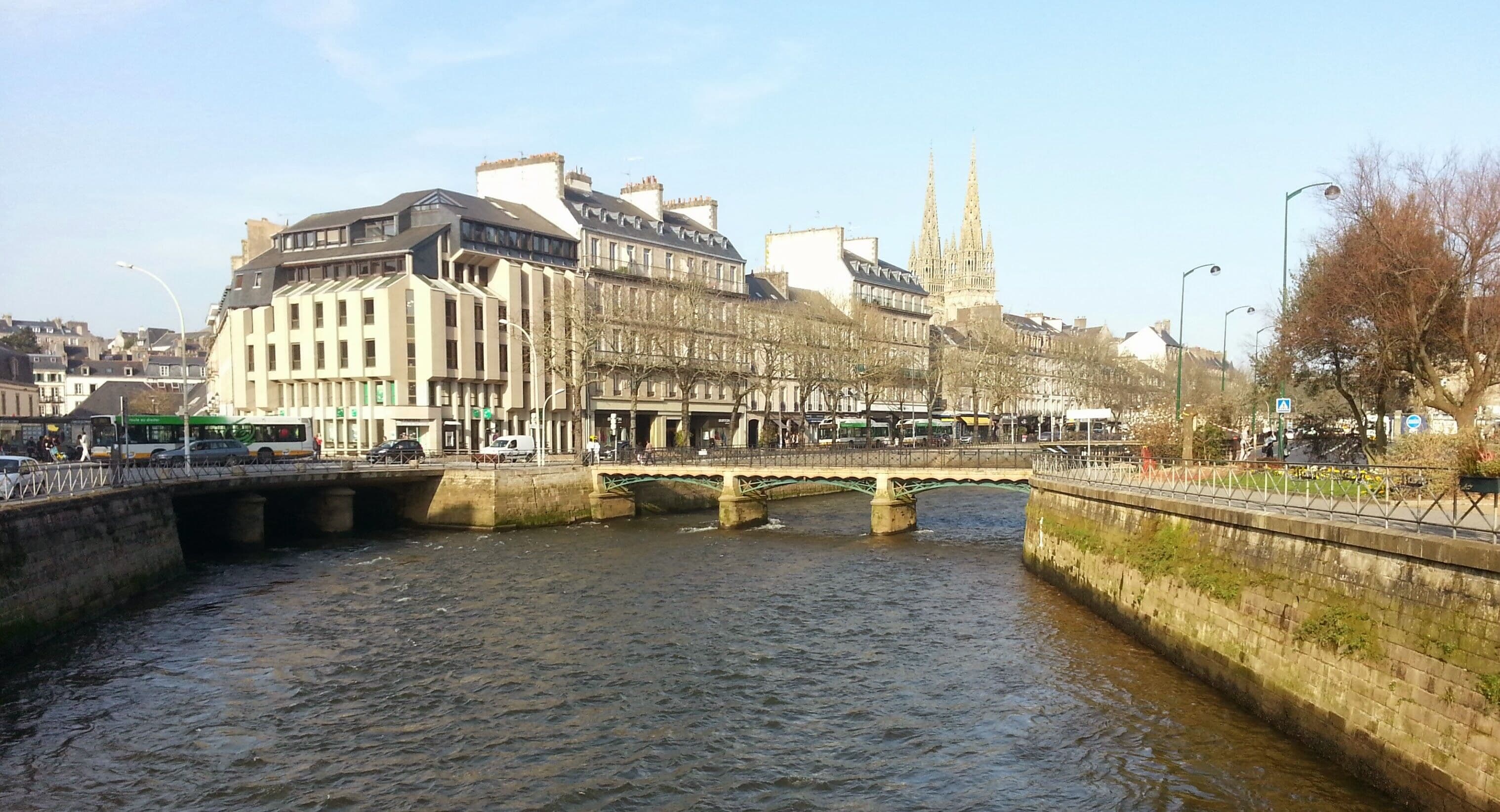 A river with a bridge, buildings, and a cathedral in the background.