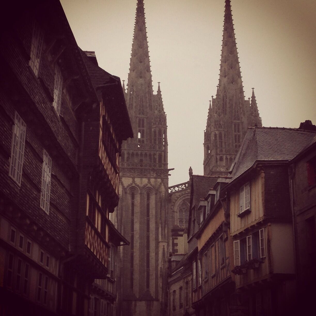 A narrow street flanked by historic buildings with pointed spires, likely a cathedral or church.