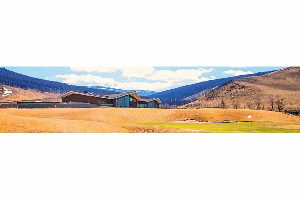 A modern house in a mountainous landscape with a flag on a hill.