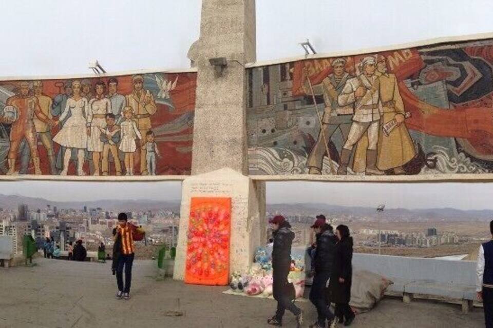 Ein großes Wandgemälde mit historischen Figuren und Szenen, einem Bergpanorama im Hintergrund und Menschen, die sich darum versammelt haben.