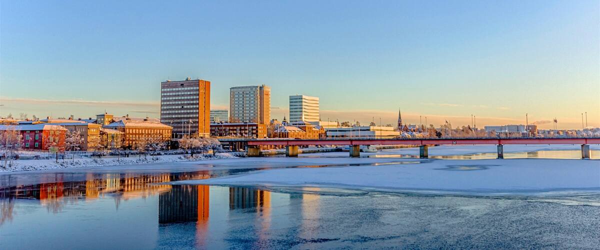 A cityscape with a frozen river, a bridge, and several modern buildings.