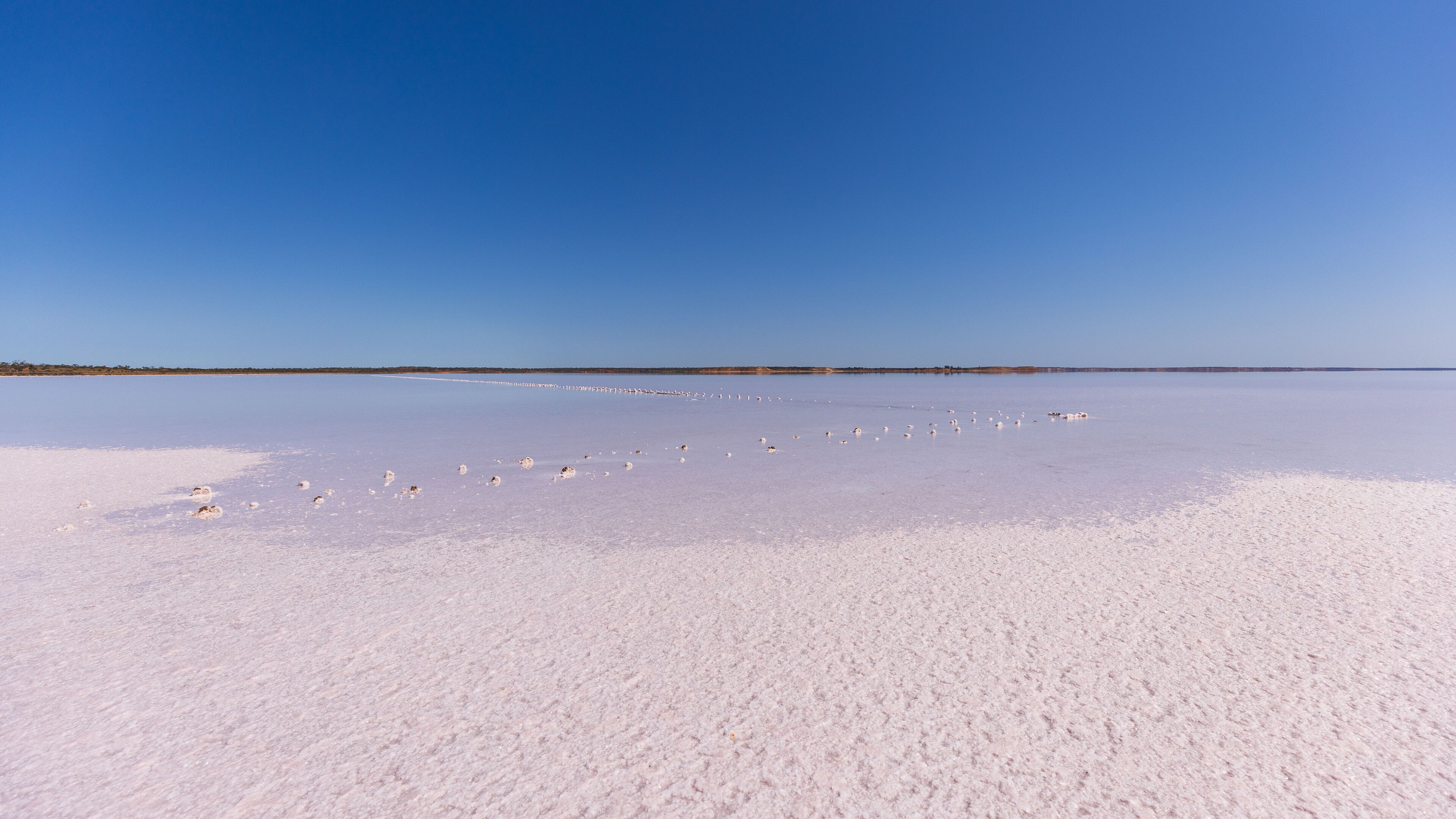 A vast salt flat under a clear blue sky.