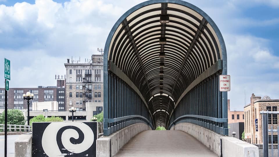 The 4th Street Bridge covered walkway in downtown Waterloo, Iowa on a beautiful summer day with clouds in the sky.