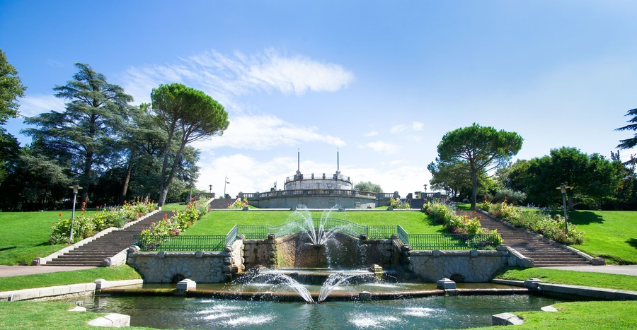 A fountain, steps, and a building in a park.