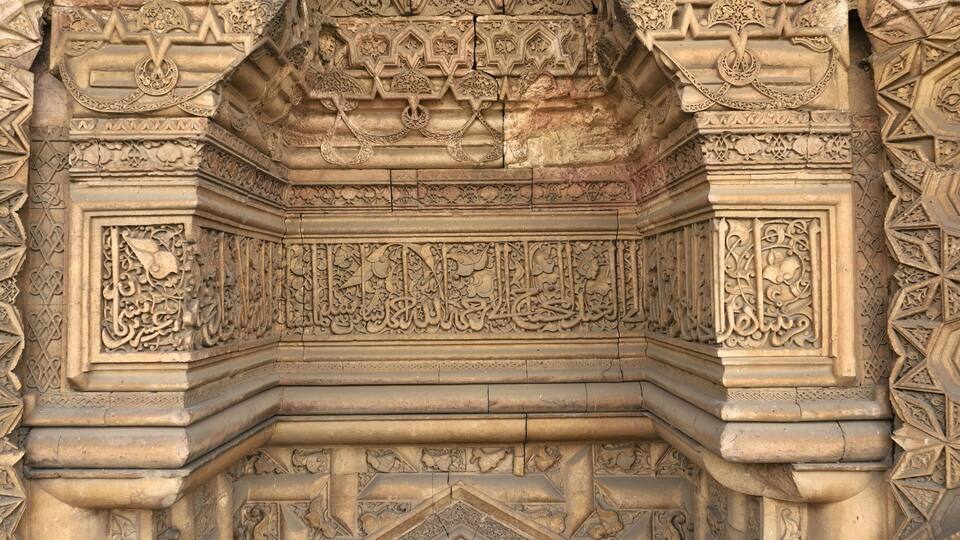 Intricate stone carvings with floral and geometric patterns, including Arabic calligraphy.