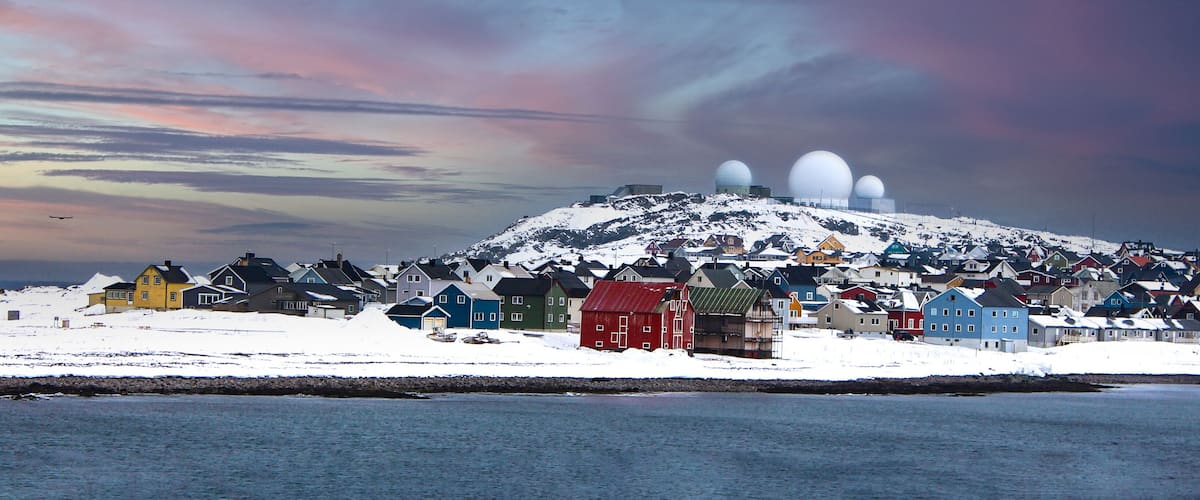 A snowy landscape with a cluster of colorful houses and a large dome structure on a hill.