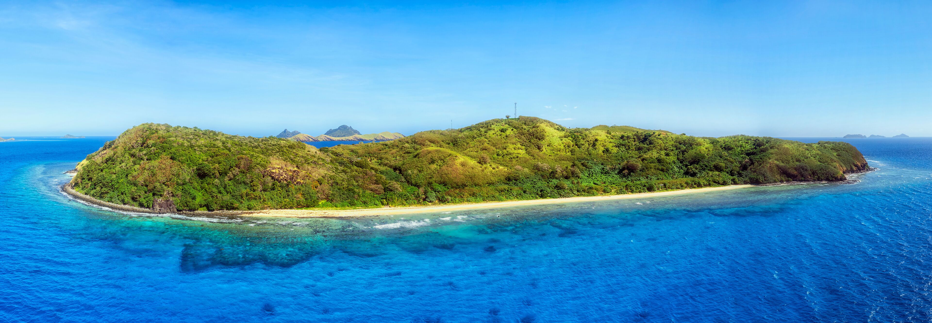 A tropical island with a sandy beach and lush greenery surrounded by clear blue waters.