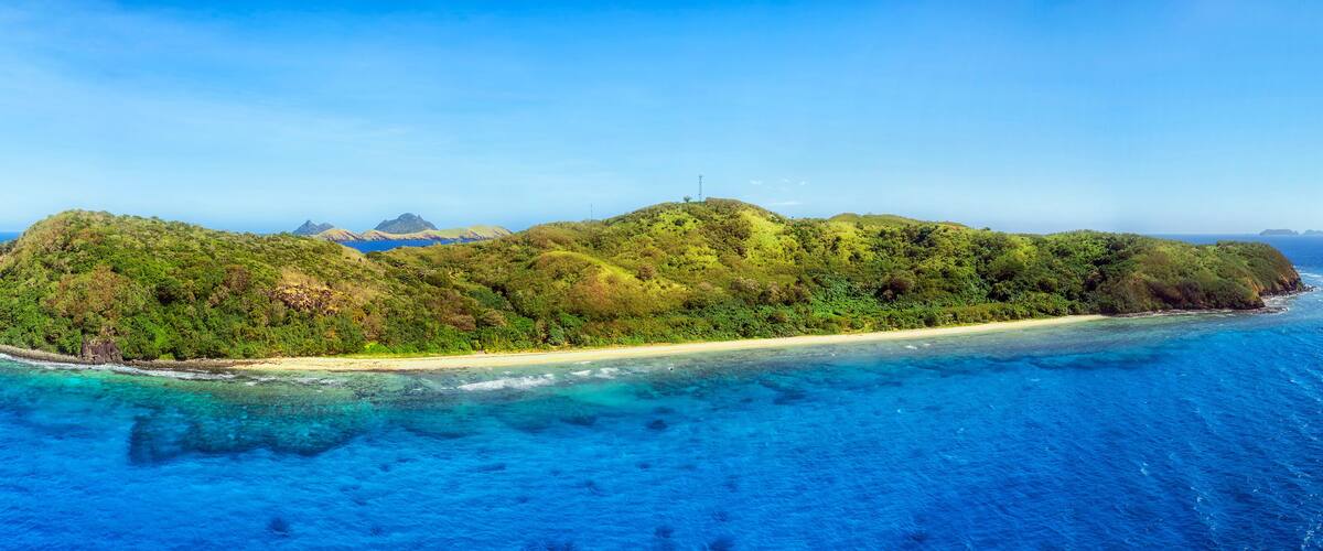 A tropical island with a sandy beach and lush greenery surrounded by clear blue waters.