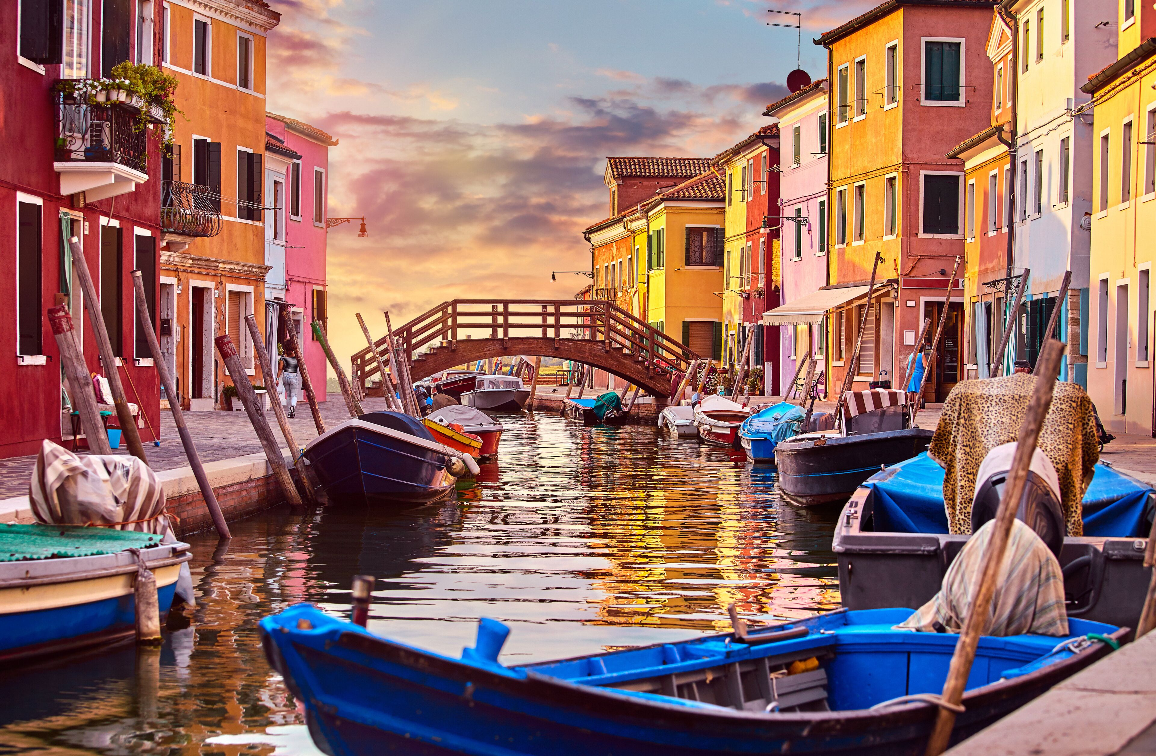 Un canal con edificios de colores, un puente de madera y barcas.