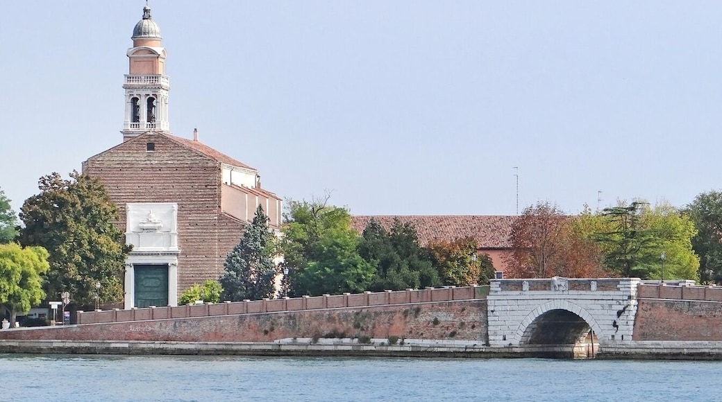 Cette église, dont la façade n'est pas terminée, a été reconstruite au XVIIè siècle avec un campanile de style baroque (1626). Sur ce site, situé au nord du Lido, il existait une église depuis 1044, dédiée à Saint Nicolas, le saint patron des marins. L'église, puis le monastère situé à proximité, ont conservé dès 1099 des reliques du Saint, ce qui en a fait un lieu de pèlerinage. Dans cette église, une messe concluait tous les ans les festivités du Mariage de Venise avec la mer comme le montre le tableau de F. Guardi. C'est aux moines bénédictins que le doge Domenico Contarini a donné le domaine de San Nicolo. Après la suppression de l'ordre des bénédictins en 1770, le monastère a été repris par des moines franciscains. Le couvent est devenu aujourd'hui le centre européen inter-universitaire pour les droits de l'Homme et la démocratisation. Il accueille des cours, séminaires, expositions,.. www.eiuc.org/ Le pont de San Nicolo date du XVIè siècle, il a été construit par l'architecte vénitien Francesco Malacrida qui a prévu des sièges de pierre pour les soldats qui devaient y monter la garde. A proximité se trouve le fort San Nicolo qui faisait face au fort San Andrea, situé sur l'île en face du Lido. Ces deux forts protégeaient l'entrée principale de la lagune (passe du Lido). Article de Wikipedia en.wikipedia.org/wiki/San_Nicol%C3%B2_al_Lido