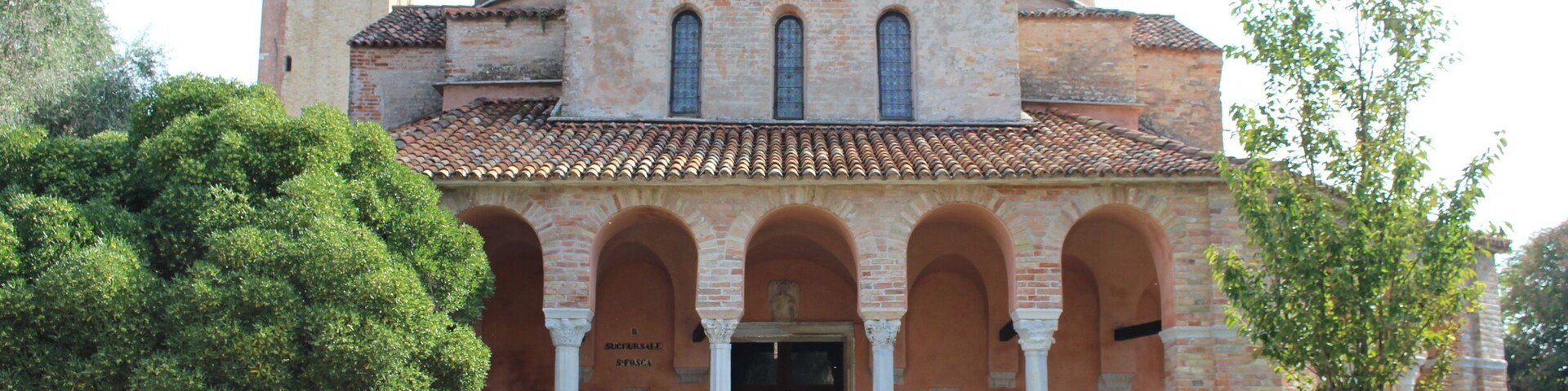 Una iglesia histórica con una cúpula central, un pórtico en arco y un campanario.