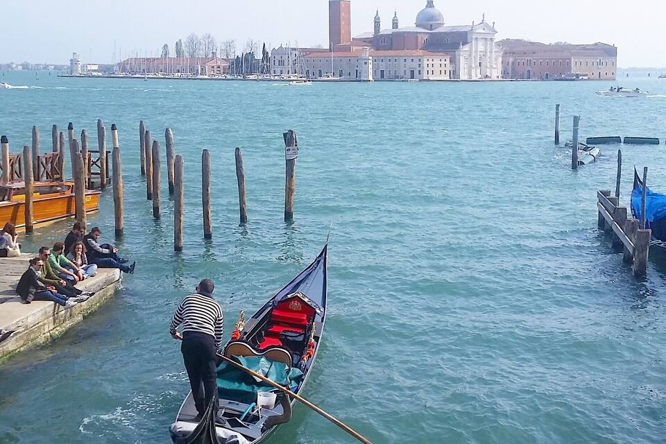 A gondola on a canal with a historic building in the background.