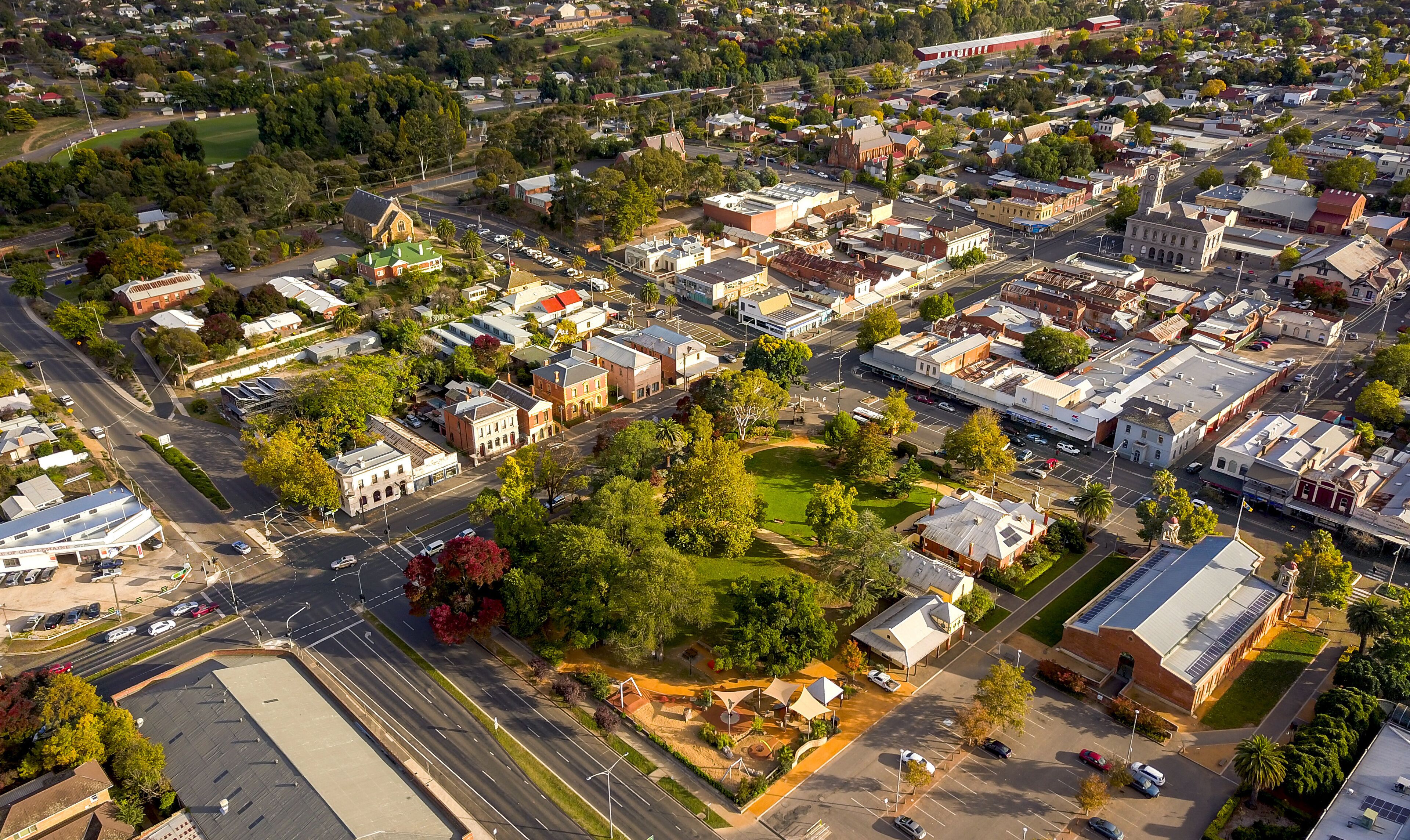 An aerial view of a town with a mix of residential and commercial buildings, a prominent church, and a railway line.