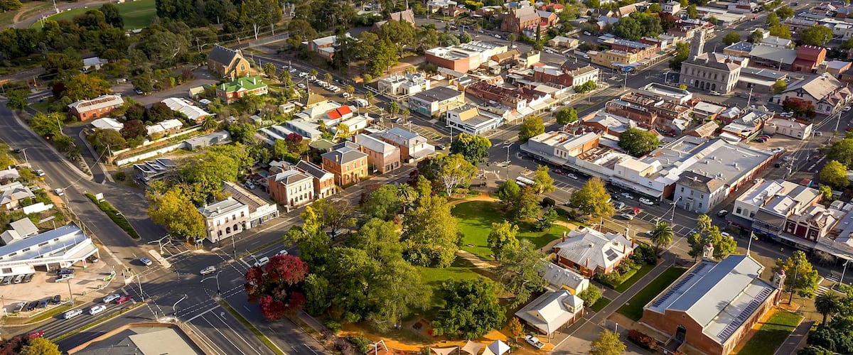 An aerial view of a town with a mix of residential and commercial buildings, a prominent church, and a railway line.