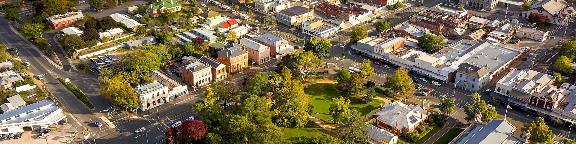 An aerial view of a town with a mix of residential and commercial buildings, a prominent church, and a railway line.