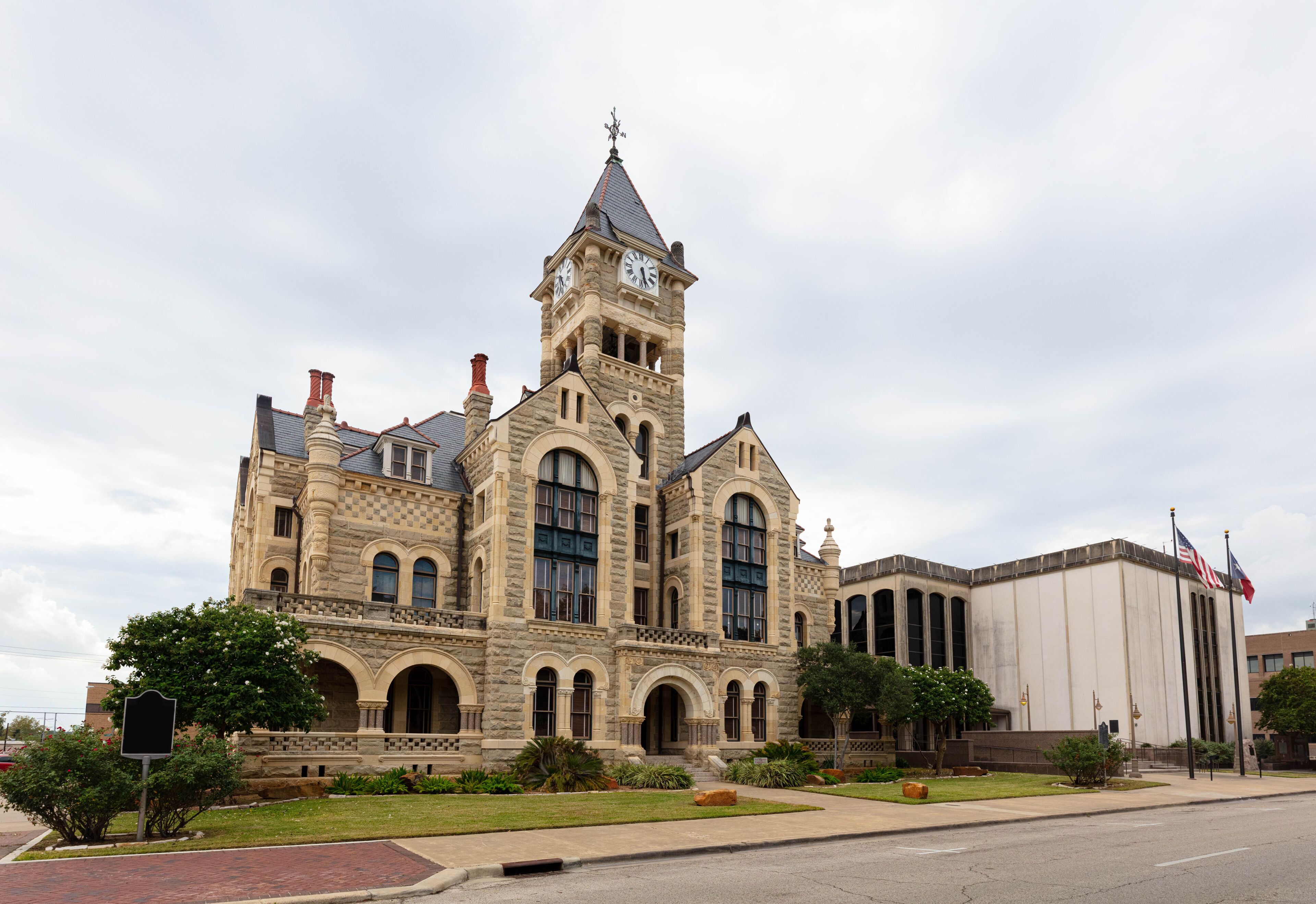A historic building with a clock tower, arched windows, and a flagpole.