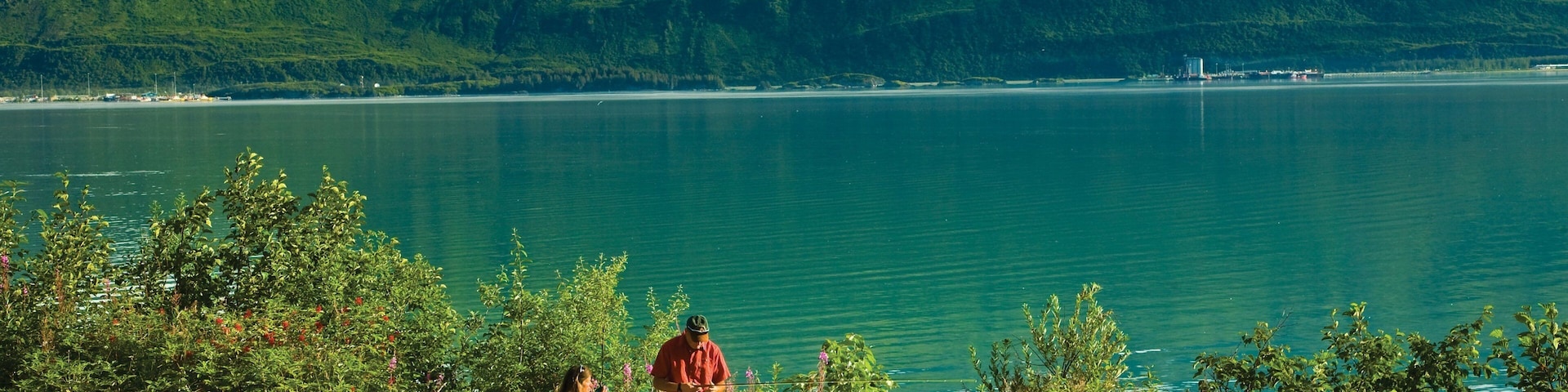 Um lago com montanhas ao fundo, uma mesa de piquenique e uma tenda.