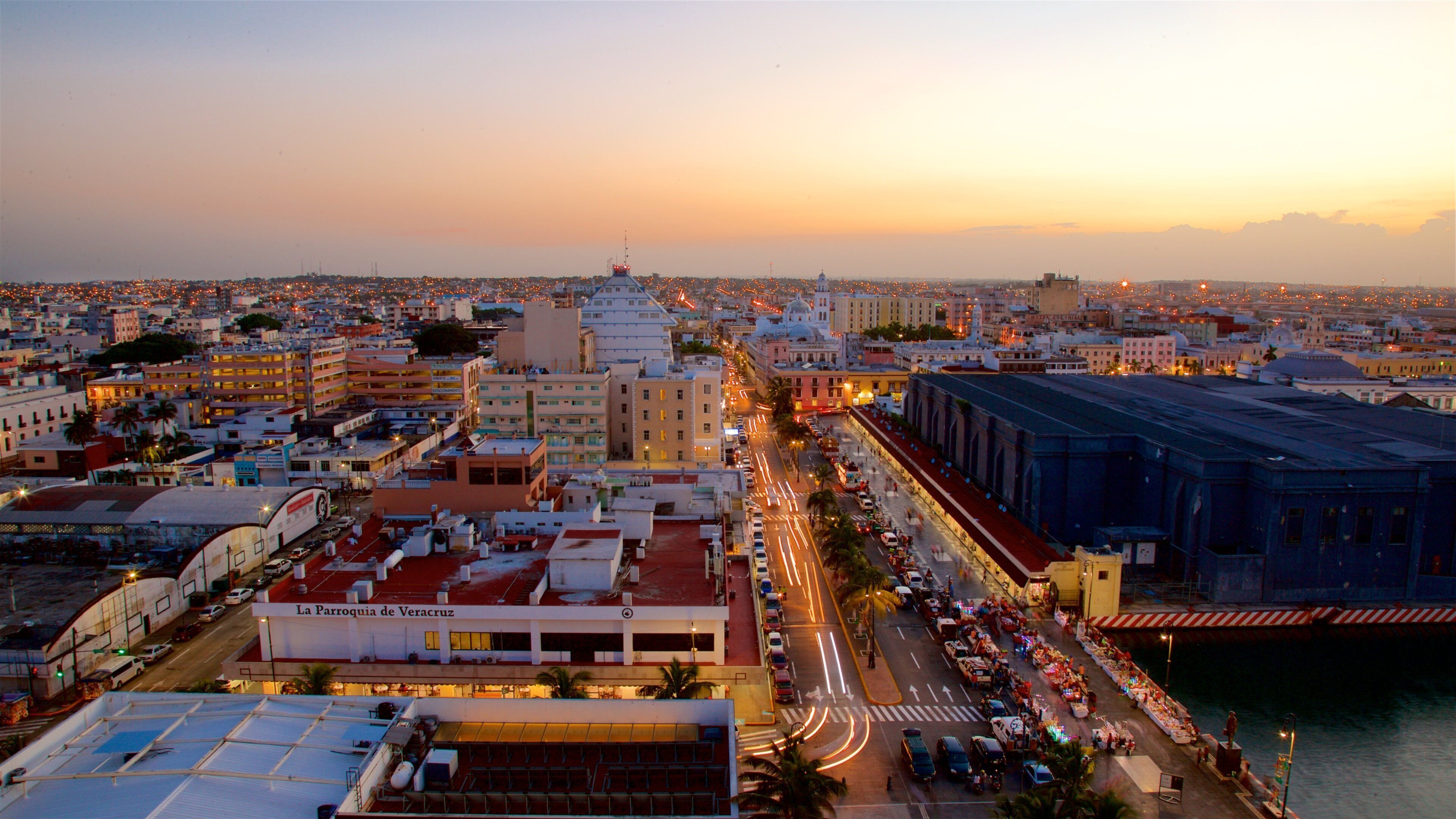A cityscape at dusk with a prominent building labeled "La Parroquia de Veracruz" and a river on the right.