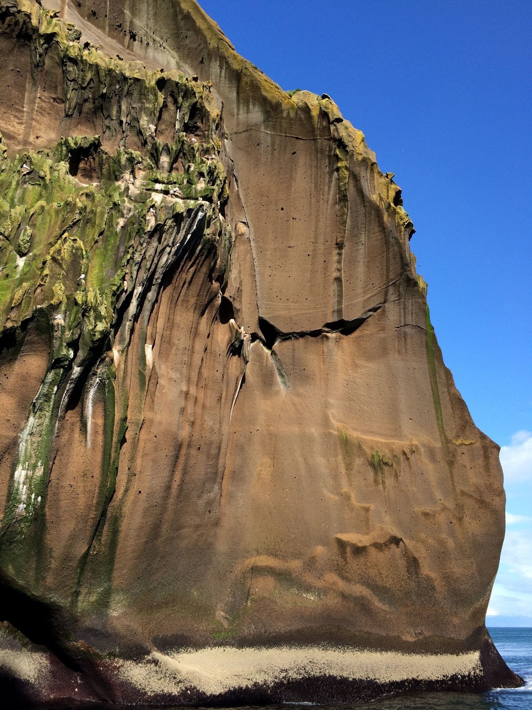 A large rock formation with visible cracks and green moss growth.