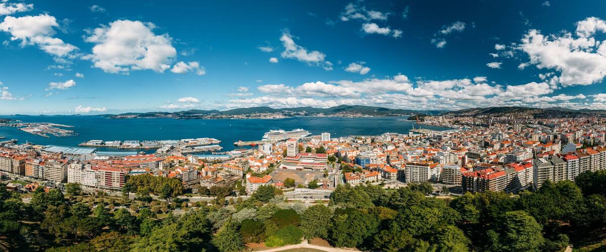 A coastal city with a harbor, ships, and a mountainous backdrop.