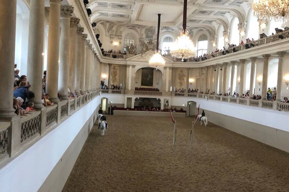 A grand hall with high ceilings, ornate columns, and a central stage.