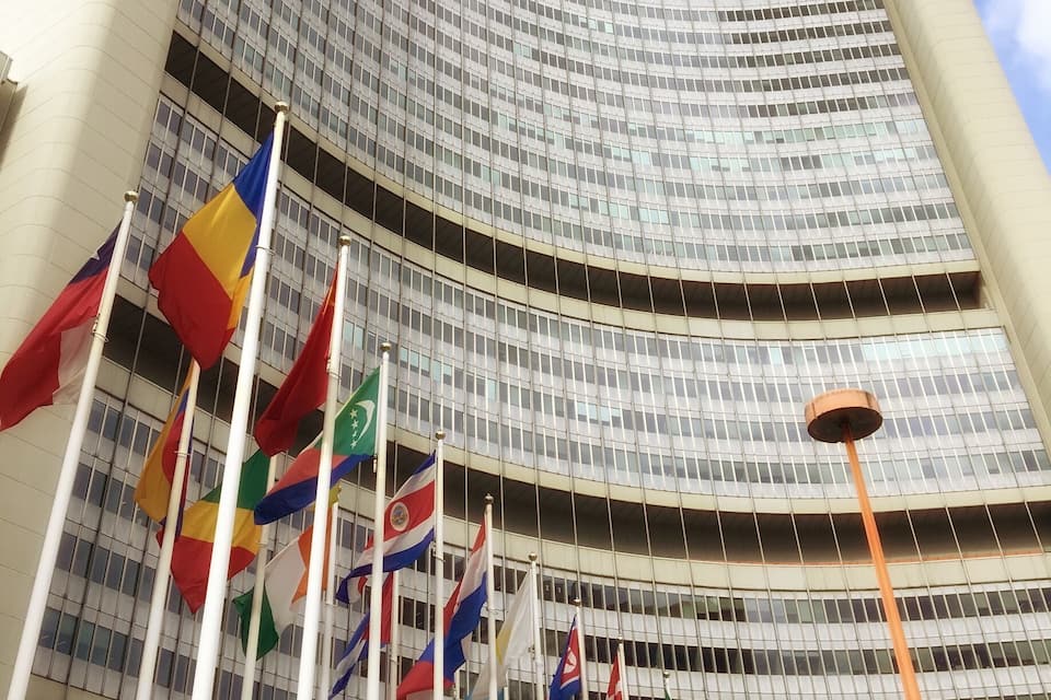 A modern building with multiple flags in front.