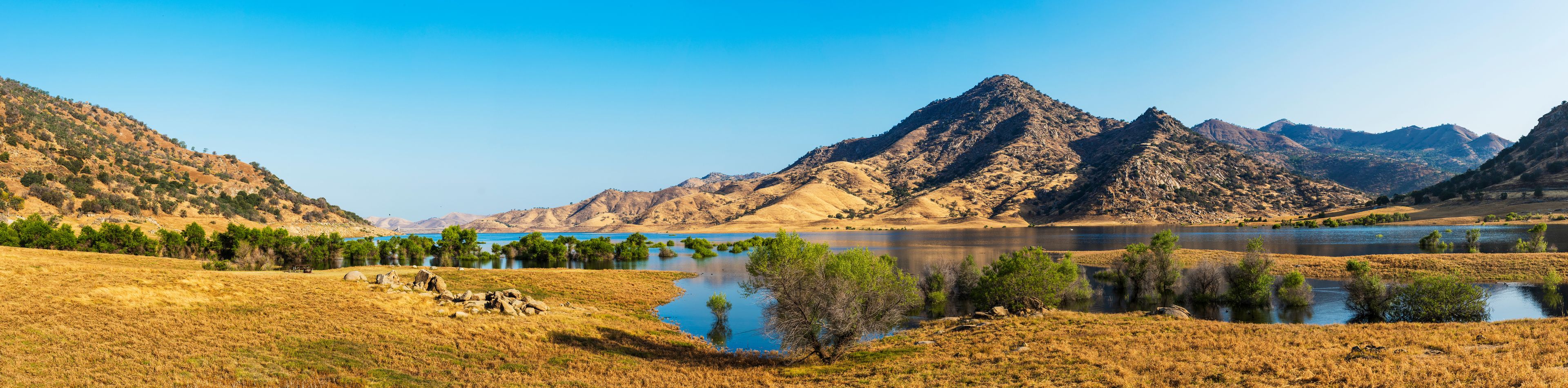 A mountainous landscape with a lake and dry grassland.