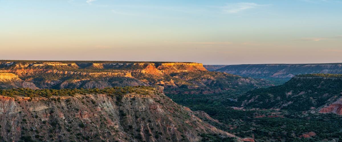 A canyon with steep cliffs and sparse vegetation.