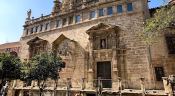 The primitive church of Sant Joan Mercat was erected in the suburb of the city known as the Boatella. From its old Gothic structure there is still the nave and the large blind oculus, known as "La O de Sant Joan", which was conceived as a large rosette on the façade of the feet.
In 1592 the church suffered a spectacular fire that forced an almost total reconstruction throughout the seventeenth and eighteenth centuries. It stands out for the infrequent the wide façade of the Market, conceived as a grandiose stone altarpiece on a terrace that dominates the square in front of the Lonja, forming a unique urban set.
It is presided by the sculpture of the Virgin of the Rosary, work in stucco by Jacopo Bertesi, and on it stands the clock tower, flanked by the two Santos Juanes and crowned by the famous "Pardal de Sant Joan", the weather vane to which -according to tradition- was made to look at the children when their humble parents abandoned them in the square. In the lower part of the terrace there are "les covetes de Sant Joan", semi-basements in which once were junkyards and old shops, part of the living history of Valencia.
The interior of the temple is an overflowing Baroque imagination, with statues of Bertesi representing characters of the Twelve Tribes of Israel, and especially the set of frescoes that Antonio Palomino executed in the vault.
