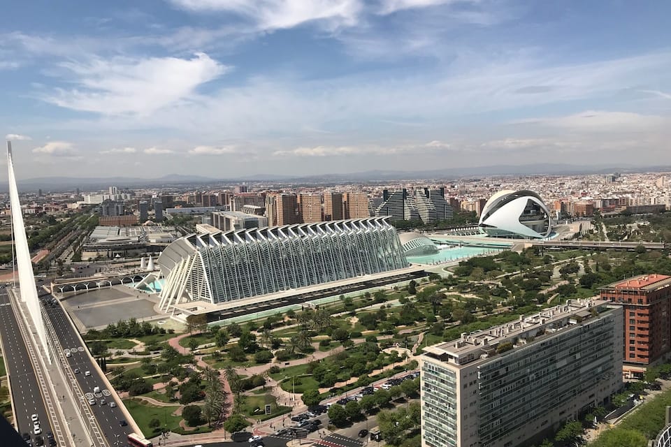 Paisagem urbana com arquitetura moderna, incluindo um edifício curvo marcante e uma torre branca alta.