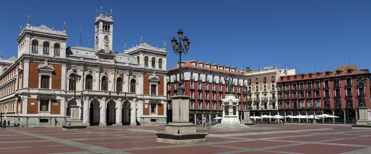 A historic building with ornate architecture, a clock tower, and a plaza with outdoor seating.