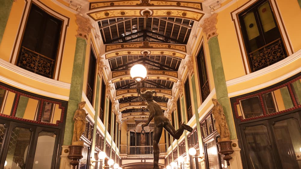 An ornate interior with a high ceiling, decorative moldings, and a central light fixture.