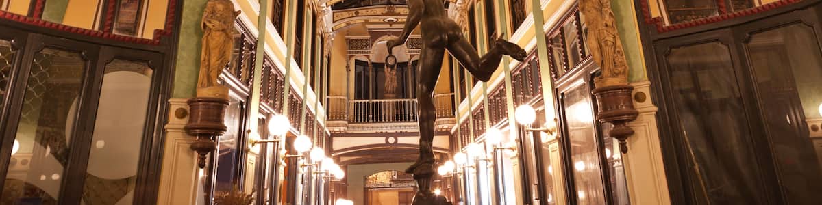 Un intérieur richement décoré, avec un plafond haut, des moulures ornementales et un luminaire central.
