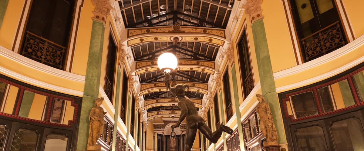 An ornate interior with a high ceiling, decorative moldings, and a central light fixture.